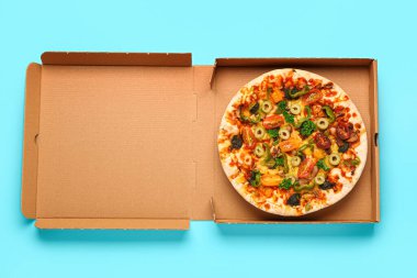 Mavi arka planda sebze pizzası olan karton kutu.