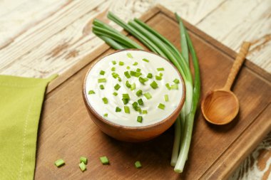 Hafif ahşap arka planda yeşil soğanlı bir kase lezzetli ekşi krema