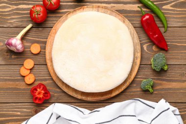 Ahşap arka planda sebze turtası hazırlamak için hamur ve malzemelerle dolu bir tahta.