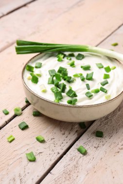 Hafif ahşap arka planda yeşil soğanlı bir kase lezzetli ekşi krema