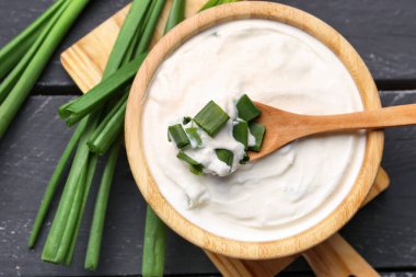 Koyu ahşap arka planda yeşil soğanlı bir kase lezzetli ekşi krema.