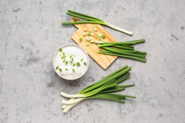 Bir kase lezzetli ekşi krema ve arka planda yeşil soğan.