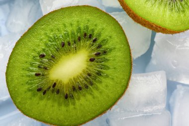 Mavi arka planda dilimlenmiş taze kivi ve buz.