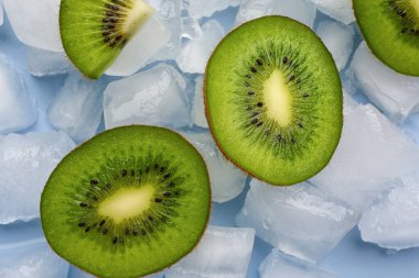 Mavi arka planda dilimlenmiş taze kivi ve buz.