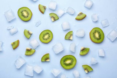 Mavi arka planda dilimlenmiş taze kivi ve buz.