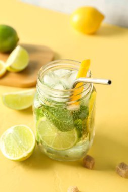 Sarı arka planda bir kavanoz lezzetli mojito.