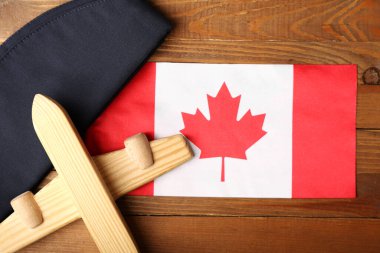 Kanadalı hostes şapkası ve oyuncak uçağıyla ahşap arka planda, yakın plan