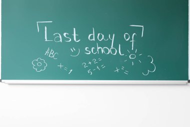 Okulun son günü yazılı karatahta ve beyaz duvardaki çizimler