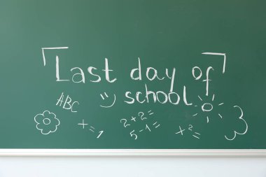 Okulun son günü yazılı karatahta ve beyaz duvardaki çizimler