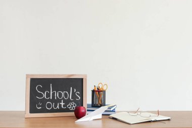 Kağıt tahtada yazı tahtası yok, elma, kağıt uçak ve kırtasiye malzemesi ışıklı duvarın yanında.