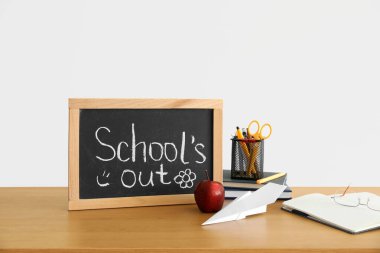 Kağıt tahtada yazı tahtası yok, elma, kağıt uçak ve kırtasiye malzemesi ışıklı duvarın yanında.