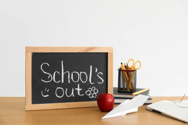 Kağıt tahtada yazı tahtası yok, elma, kağıt uçak ve kırtasiye malzemesi ışıklı duvarın yanında.