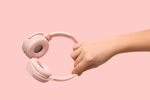 ピンクの背景に現代的なヘッドフォンを持っている女性 — ストック写真