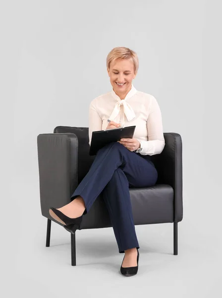 Mature Businesswoman Clipboard Sitting Armchair Grey Background — Stock Photo, Image