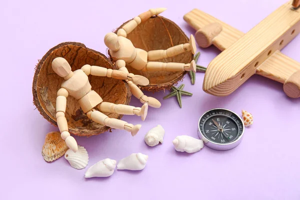 Composition with wooden plane, compass and mannequins sitting in coconut shell on lilac background