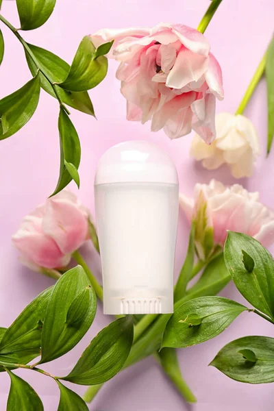 stock image Deodorant bottle, leaves and flowers on pink background