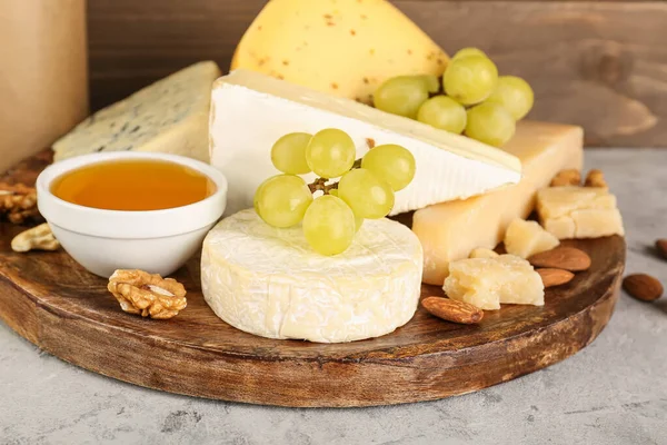 stock image Plate with different types of cheese, honey and grapes on table