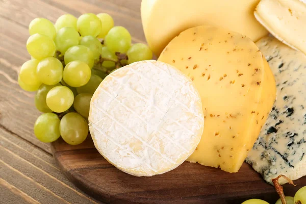 不同类型的奶酪和葡萄 木制背景 — 图库照片