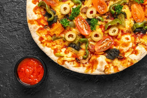 Vegetable pizza with sauce on dark background