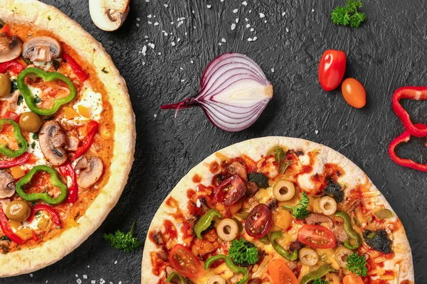 Vegetables pizzas with ingredients on dark background
