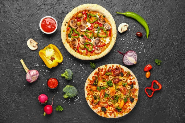 Vegetables pizzas with ingredients and sauces on dark background
