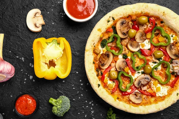 Vegetable pizza with ingredients and sauce on dark background