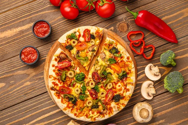 Board with vegetable pizza and ingredients on wooden background