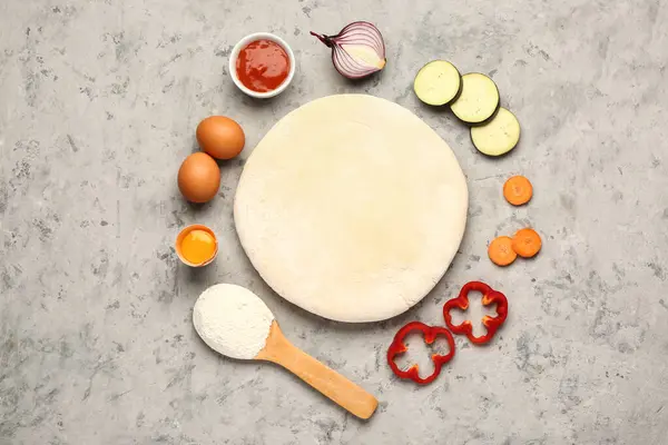 stock image Raw dough and ingredients for preparing vegetable pie on grey grunge background