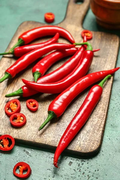 stock image Wooden board with fresh chili peppers on green background