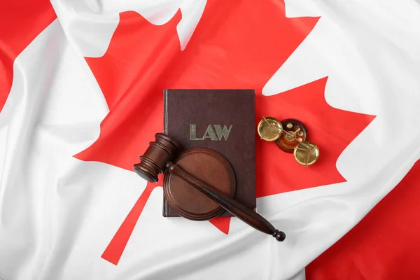 stock image Judge's gavel with law book and justice scales on flag of Canada