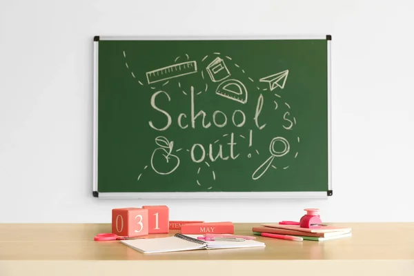 stock image Blackboard with text SCHOOL'S OUT, drawings and desk in classroom