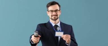 Mavi arka planda mikrofonu ve rozeti olan erkek gazeteci 