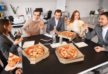 Bir grup iş adamı ofiste lezzetli pizzalar yiyor.