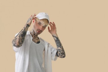 Bej arkaplanlı dövmeli genç adam.