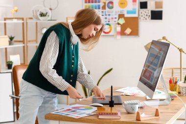 Ofisteki masada renk paletleri ile çalışan kadın grafik tasarımcısı