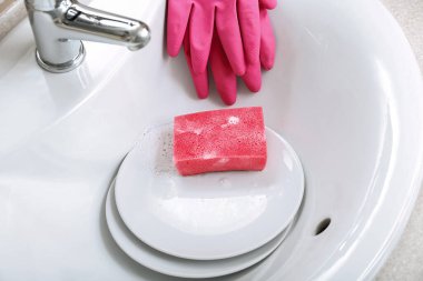 Lavaboda temizlik süngeri olan tabaklar, yakın plan.