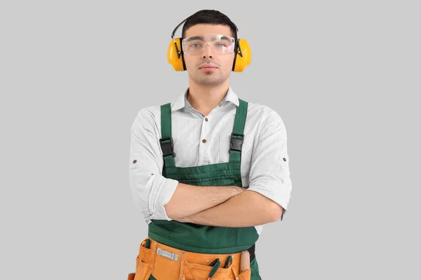 灰色背景下听力保护器的年轻木匠 — 图库照片
