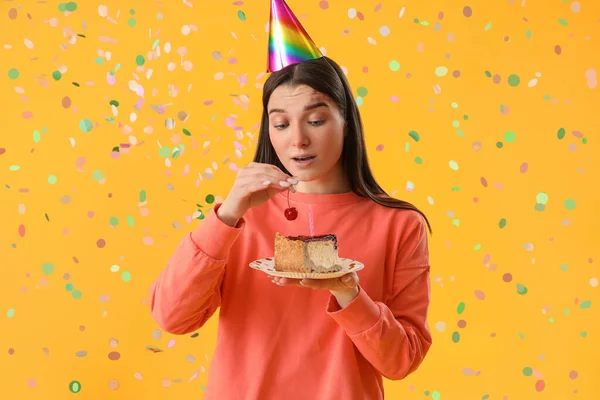 Happy young woman with cake celebrating Birthday on yellow background