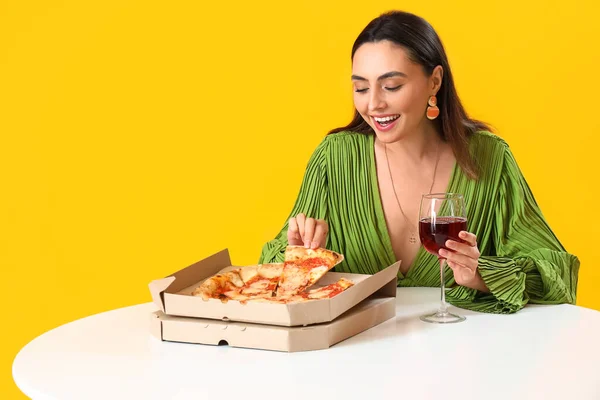 Młoda Kobieta Smaczną Pizzą Kieliszkiem Wina Przy Stole Żółtym Tle — Zdjęcie stockowe