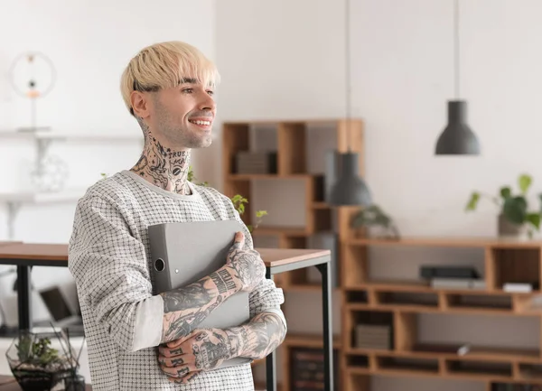 Young tattooed man with folder in office