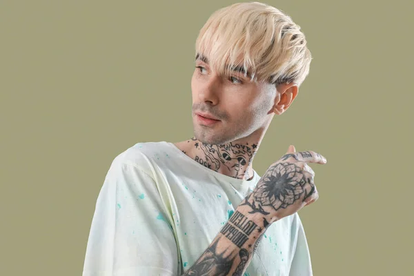 Tattooed young man on green background, closeup