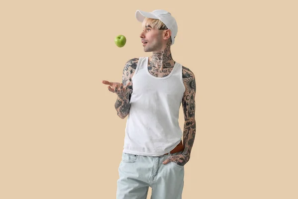 Tetovaný Mladý Muž Jablkem Béžovém Pozadí — Stock fotografie