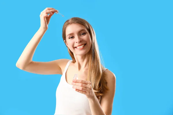 Junge Frau Verwendet Serum Für Haarwuchs Auf Blauem Hintergrund — Stockfoto