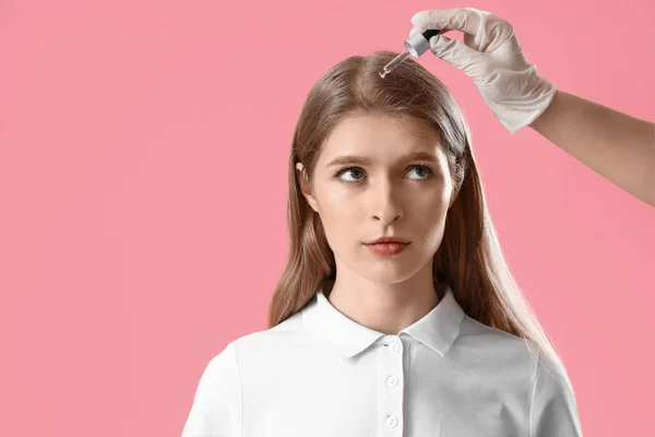 Cosmetologista Aplicando Soro Cabelo Jovem Mulher Contra Fundo Rosa — Fotografia de Stock