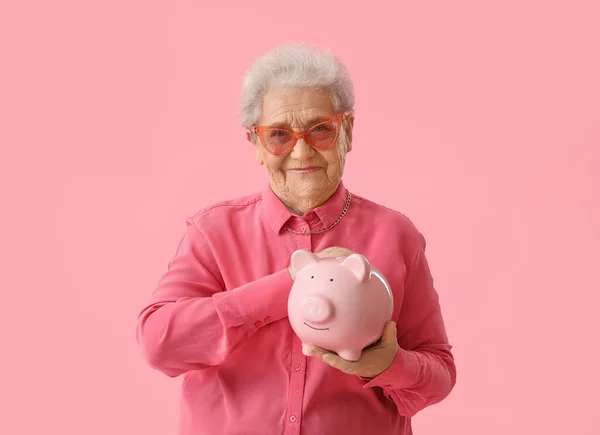 Mulher Sênior Com Banco Porquinho Fundo Rosa — Fotografia de Stock
