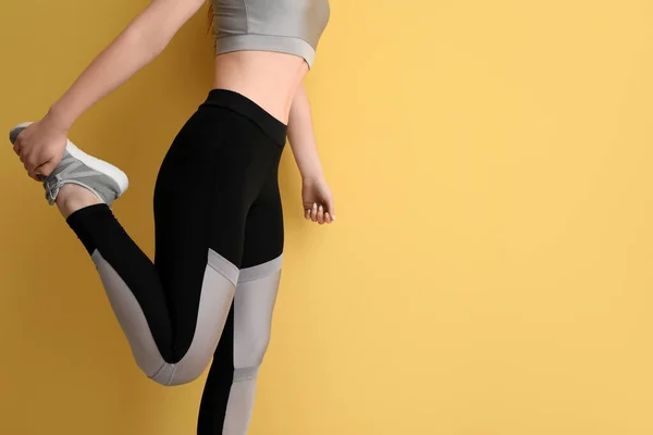 Sporty young woman in leggings on yellow background