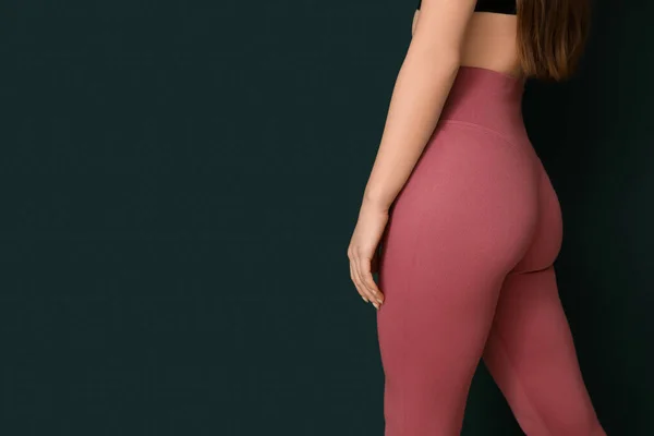Sporty young woman in leggings on green background, closeup