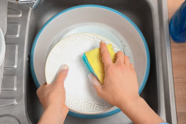 洗碗的女人用海绵在洗碗槽里 — 图库照片