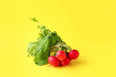 Sarı arka planda yaprakları olan taze turplar.