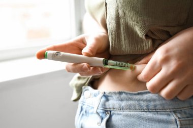 Şeker hastası bir kadın evde tükenmez kalem kullanıyor, yakın plan.